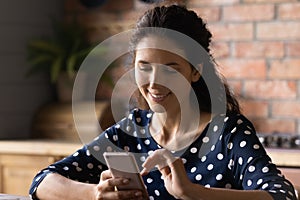 Happy Hispanic woman with smartphone using virtual app at home