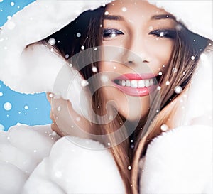 Happy holidays, beauty and winter fashion, beautiful woman wearing white fluffy fur coat, snowing snow on blue background as