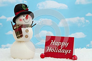 Happy holidays greeting card with snowman, ornaments, and snow with sky