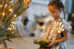 Happy holidays. Little child opening present near Christmas tree. The girl laughing and enjoying the gift.