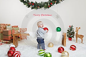 Happy holidays. Merry Christmas. Christmas card with text. Cute adorable Caucasian baby boy with the winter festive ornaments