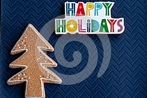 Happy Holidays plaque message and a glitter gingerbread Christmas Tree on blue background