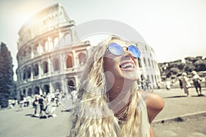 Happy holidays in Rome, smiling young blonde in front of colosseum in Rome in Italy