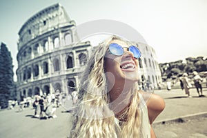 Happy holidays in Rome, smiling young blonde in front of colosseum in Rome in Italy