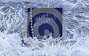 Happy holidays text on black card with silver beads on white flu