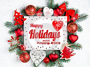 Happy Holidays and happy 2019 text with Christmas photoframe surrounded by branches of a New Year tree, red Christmas decorations