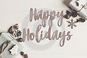 Happy holidays text, seasonal greetings card sign. flat lay. sty