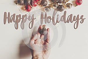 Happy holidays text, seasonal greetings card sign. hand holding