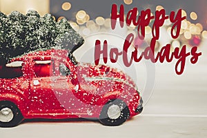 Happy holidays text, seasonal greetings card sign. red car toy w