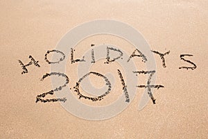 Happy Holidays 2017. Written in sand at the beach. Holiday, Christmas, New Year 2017 concept.