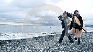 Happy homeless couple, a man and a woman running on the beach