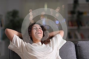 Happy homeowner relaxing on a couch at home photo