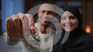 Happy homeowners african american arabian muslim multiracial diversity couple showing keys from new home real estate