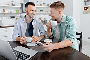 happy homosexual couple holding coffee near