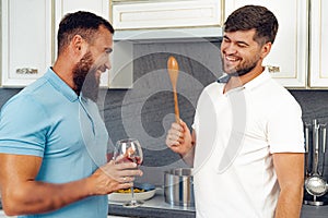 Happy homosexual couple preparing food together in kitchen