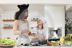 Happy homosexual lesbian LGBT couple wear apron and chef hat, cooking romantic love meal food at kitchen together, beautiful woman