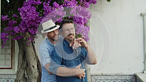 Happy homosexual man in hat hugging his boyfriend from back