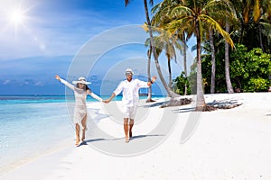 Couple walks down a tropical beach in the Maldives islands