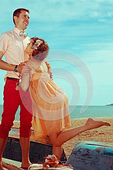 Happy honeymoon vacation concept. Young married couple of hipsters in trendy clothes standing on a boat, playing and laughing.