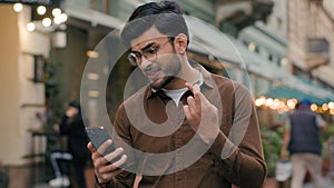 Happy hopeful lucky Indian Arabian ethnic man guy businessman male young student hold mobile phone smartphone wishing