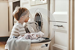 Happy  householder child boy in laundry   with washing machine
