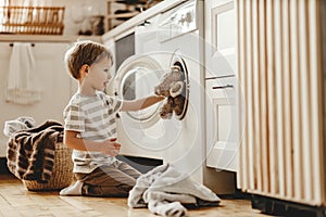 Happy  householder child boy in laundry   with washing machine