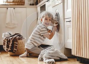 Happy  householder child boy in laundry   with washing machine