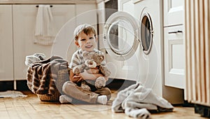 Happy  householder child boy in laundry   with washing machine photo