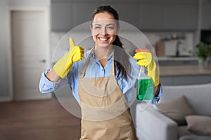 Happy housekeeper gives thumbs up with cleaning products