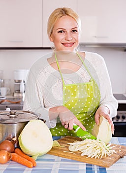 Happy housewife cooking shredded sauerkraut