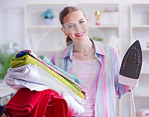 Happy housewife doing ironing at home