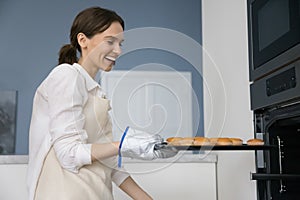 Happy housewife prepare tray with fresh baked muffins