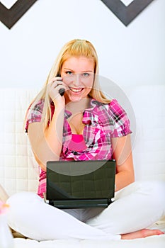 Happy housewife sitting on divan with laptop