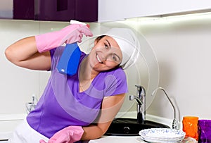 Happy housewife with a spray bottle of detergent