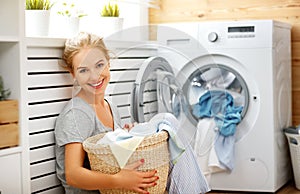 Happy housewife woman in laundry room with washing machine