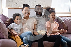 Happy hugging african family with children watching tv movie together