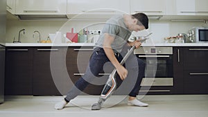 Happy husband cleaning floor at modern kitchen.