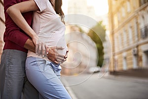 Happy husband holding tummy of his pregnant wife