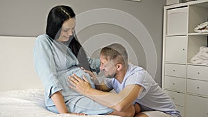 Happy husband hugs his pregnant wife, strokes her belly. Waiting for the birth of a child.