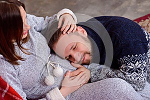 Happy husband listens to baby heartbeat lying on belly of his pregnant wife