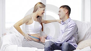 Happy husband measuring waist of pregnant wife