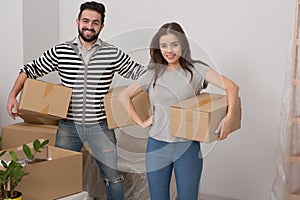 Happy husband and wife carrying boxes in their new house.