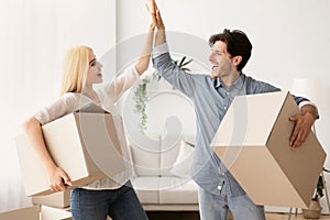Happy Husband And Wife Giving High Five Holding Moving Boxes