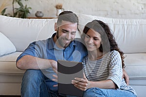 Happy husband and wife sharing tablet computer, enjoying communication