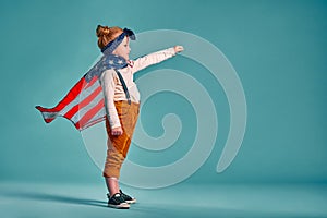 Happy independence day. Little smiling patriotic girl with an american flag waving in the wind on blue background