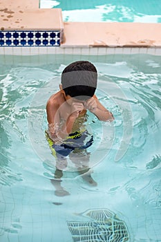 Happy Indian boy swimming in a pool, Kid wearing swimming costume along with air tube during hot summer vacations, Children boy in