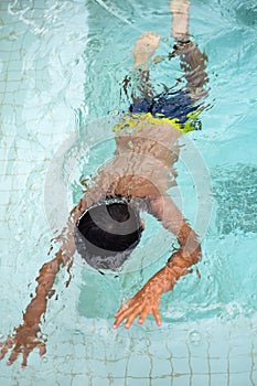 Happy Indian boy swimming in a pool, Kid wearing swimming costume along with air tube during hot summer vacations, Children boy in