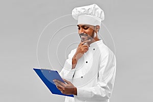 Happy indian chef reading menu on clipboard