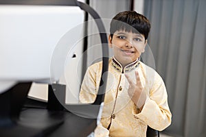 Happy Indian child boy examining eyesight modern ophthalmology equipment in clinic. Patient kid male scan checkup iris examines