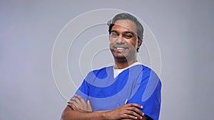 happy indian doctor or male nurse in blue uniform